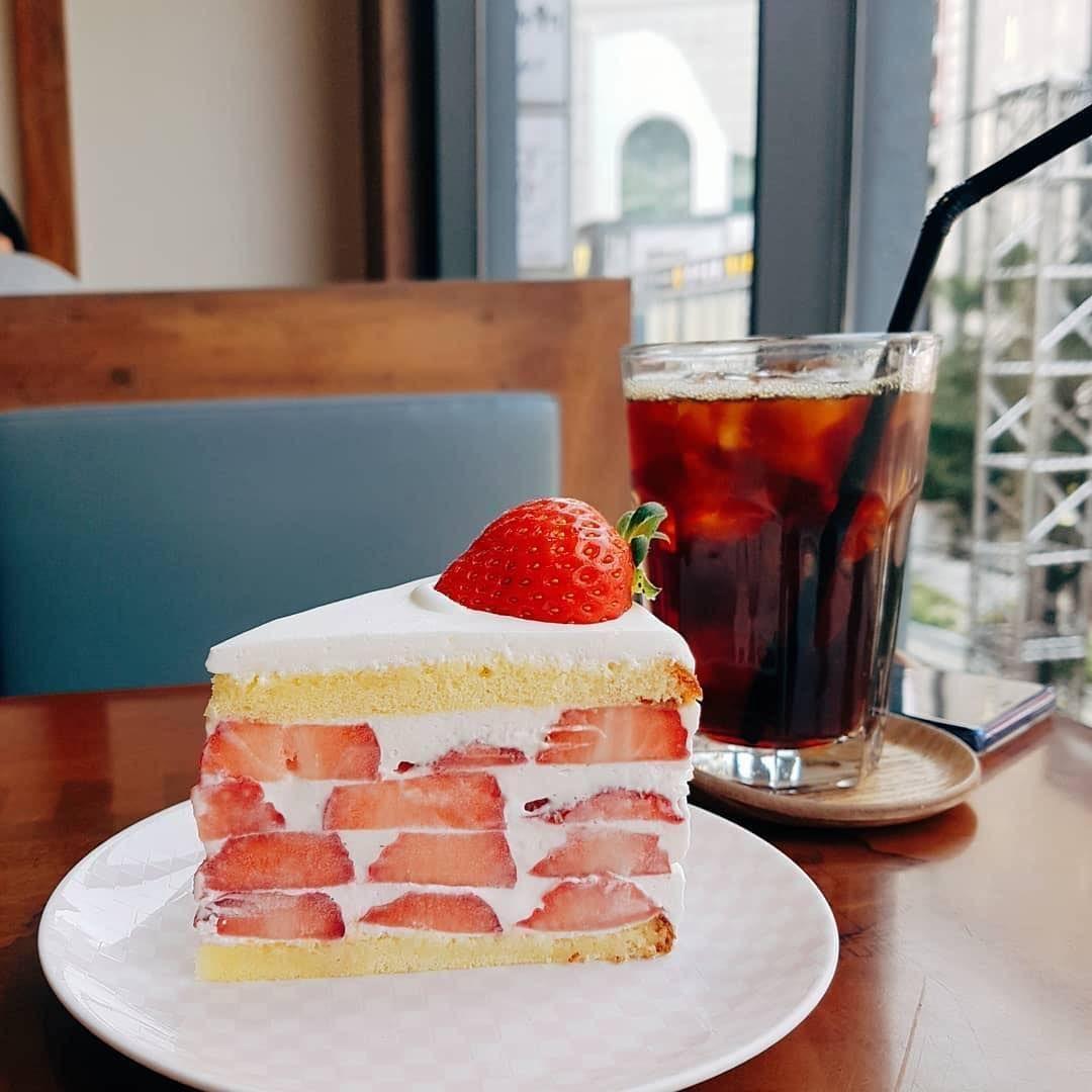 Bánh dâu tây bên cạnh ly cà phê đá, tạo nên một trải nghiệm ẩm thực hoàn hảo tại Coffee Myungga.