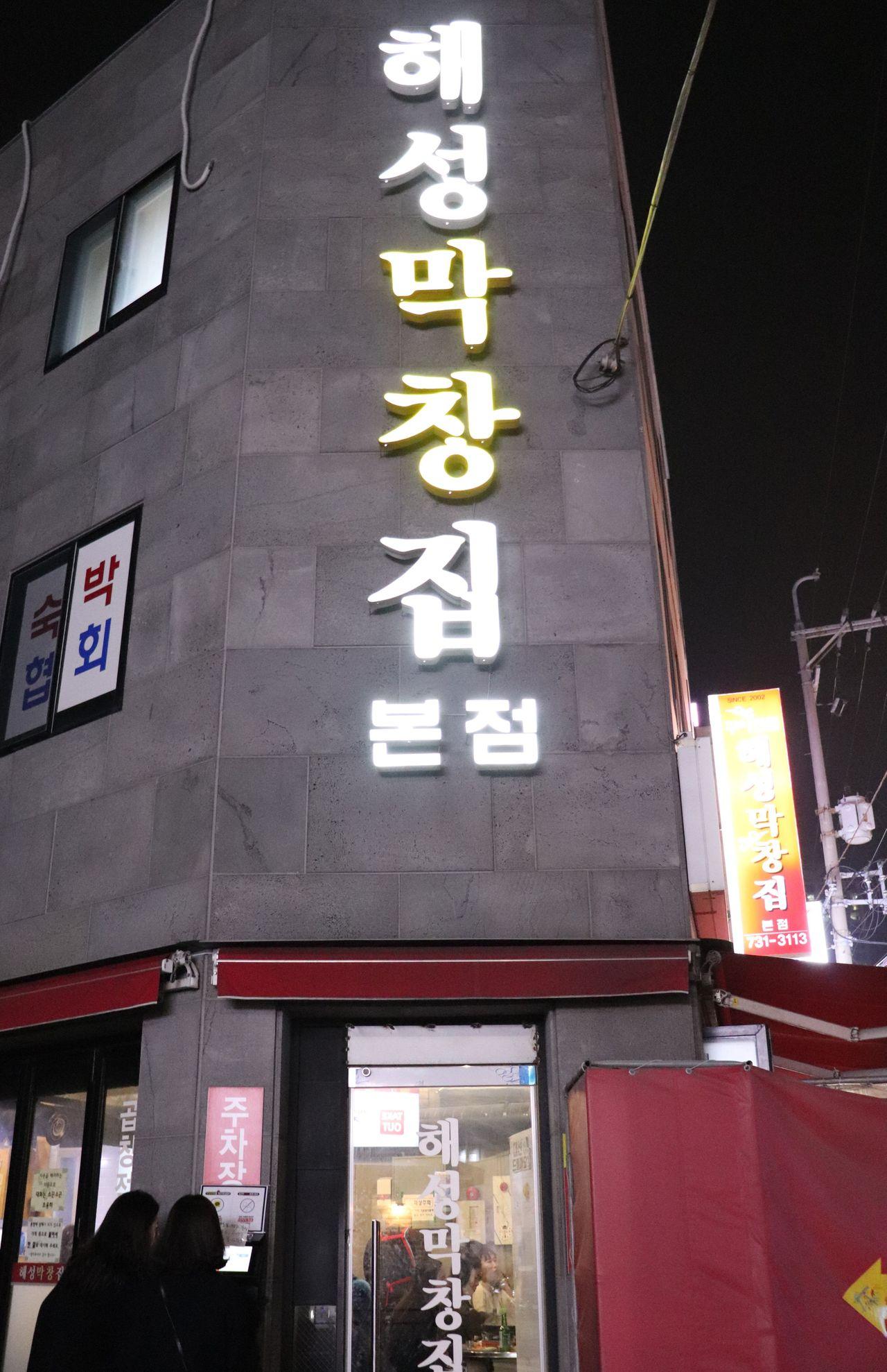 海城烤腸店在夜晚的招牌，被很多顧客包圍。