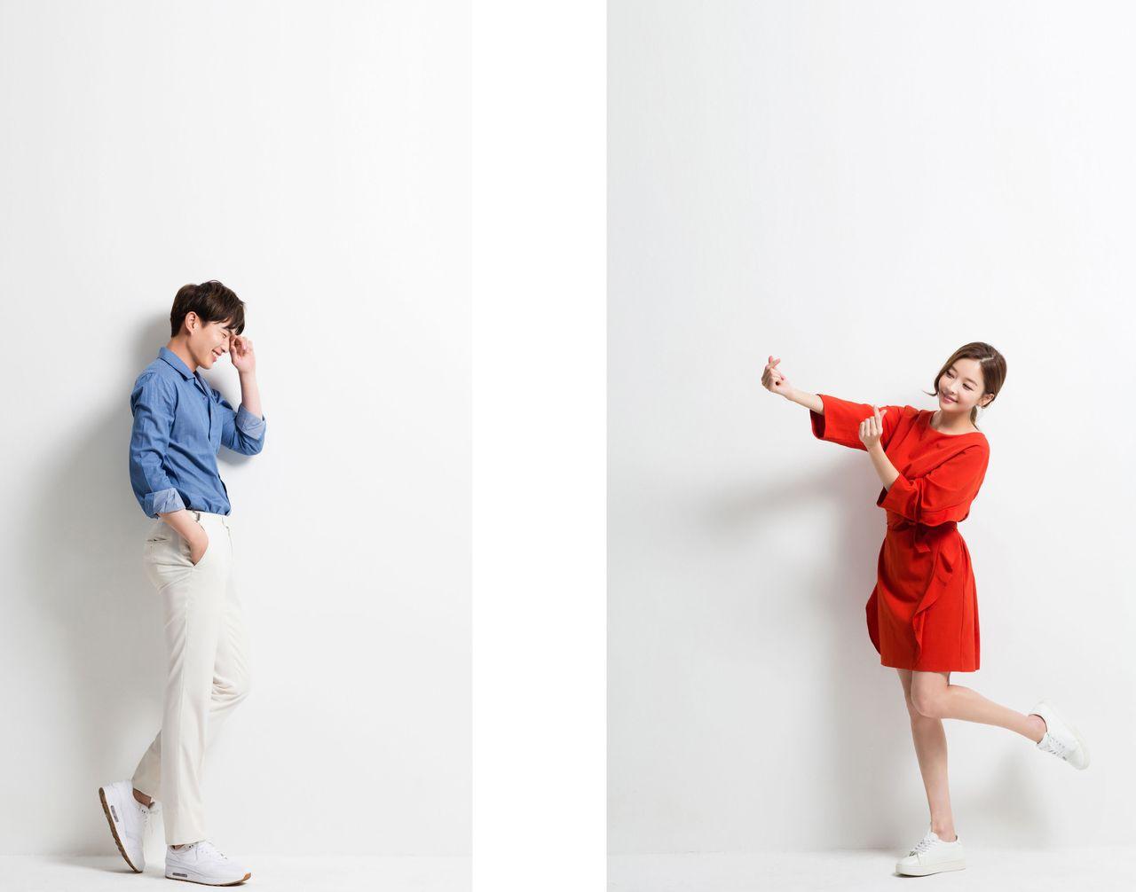 Engaged couple posing with flowers against a minimal blue backdrop, highlighting the serene nature of Korean wedding portraits.