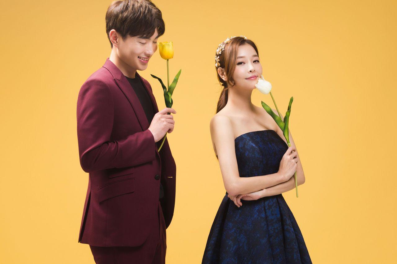 Engaged couple in formal wear on a plain background, reflecting Korean wedding photo style at Time On Me Studio.
