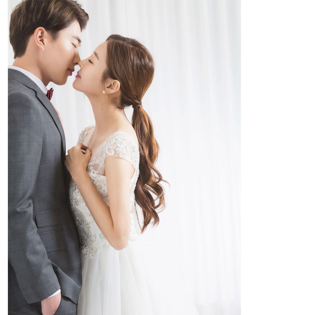 Bride leaning against groom, both elegantly dressed, embodying the romantic essence of Korean wedding photos.