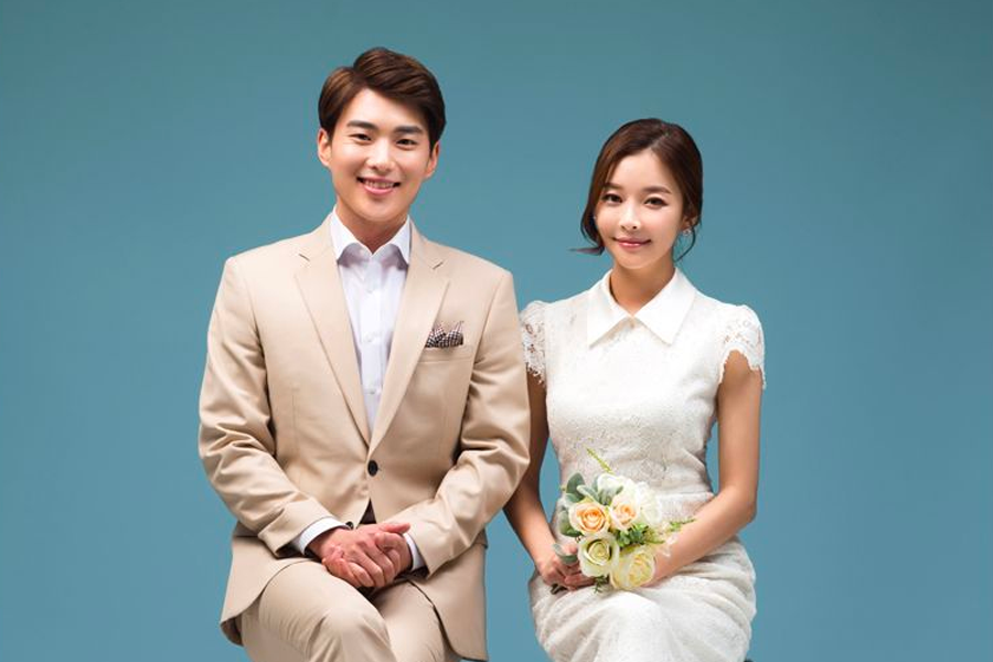 身著白色蕾絲連衣裙的新娘，單獨站立，手持花朵，展現優雅婚紗攝影的魅力。