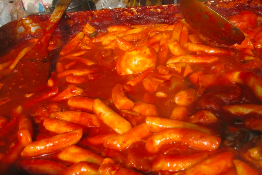 Large batch of spicy Korean Tteokbokki simmering in sauce, a staple street food snack known for its bold flavors.