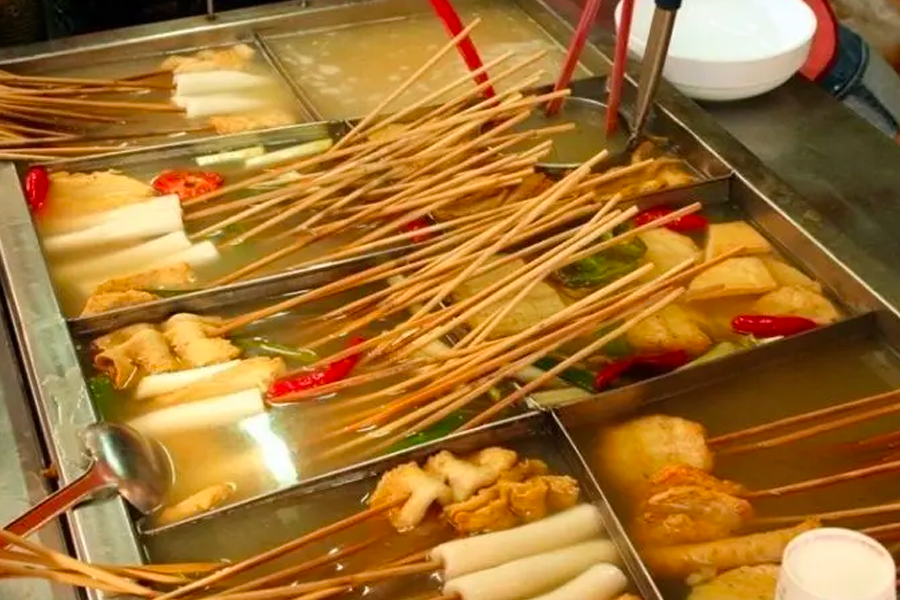 Multiple skewers of Korean fish cakes boiling in street vendor soup, a warm and hearty snack during colder months.