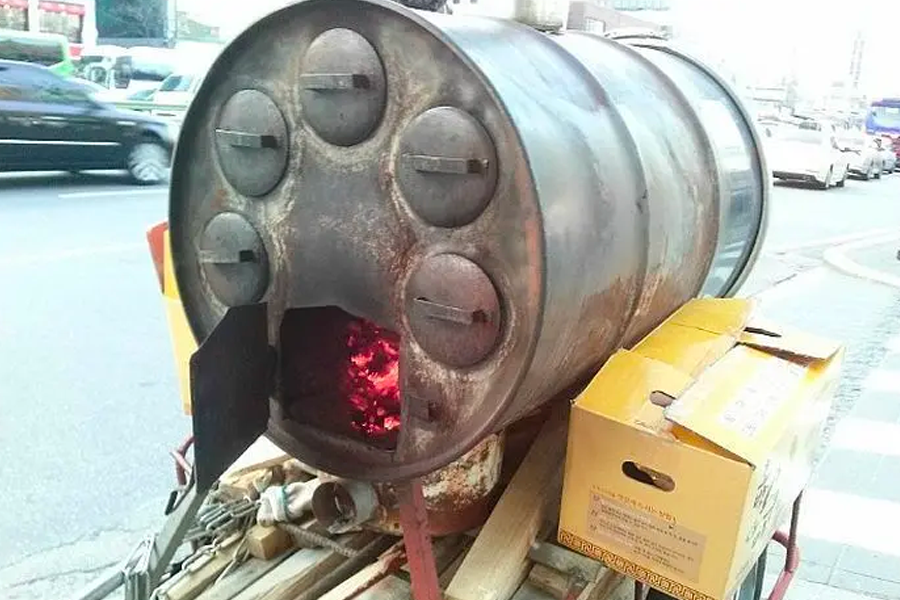 Traditional street food stove for roasting sweet potatoes in Korea, preparing to serve warm treats in winter.