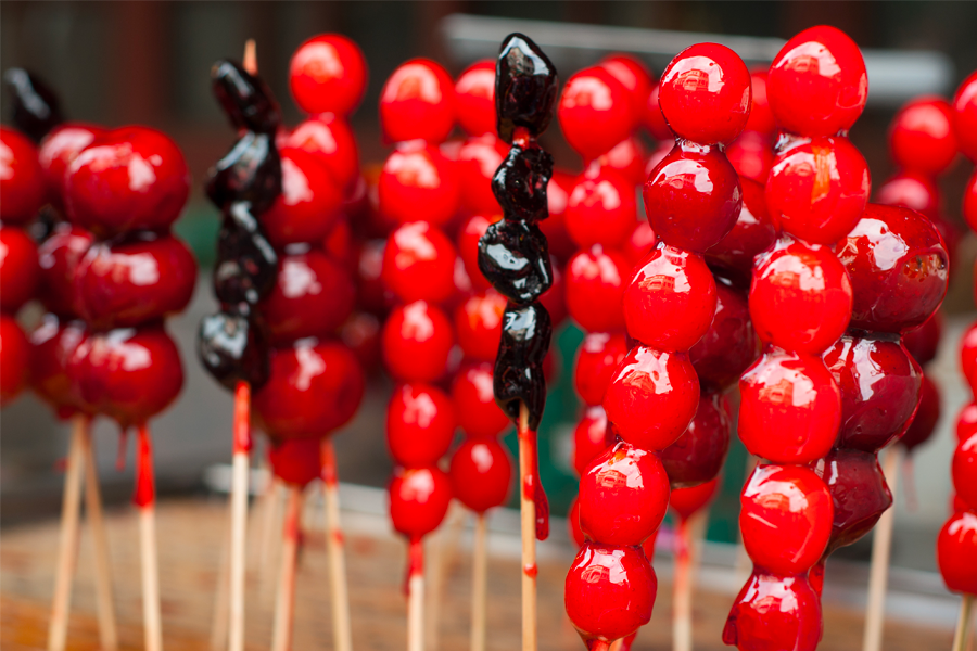 Vibrant lineup of colorful Korean Tanghulu skewers, showcasing fruits covered in shiny, hard sugar coating.