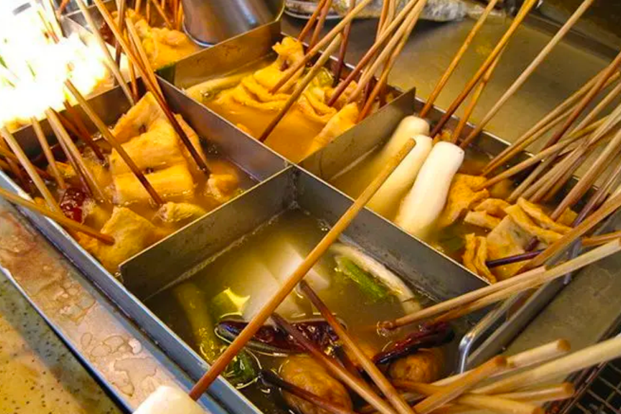 A variety of Korean street food skewers, including fish cakes and tteokbokki, simmering in flavorful broth.