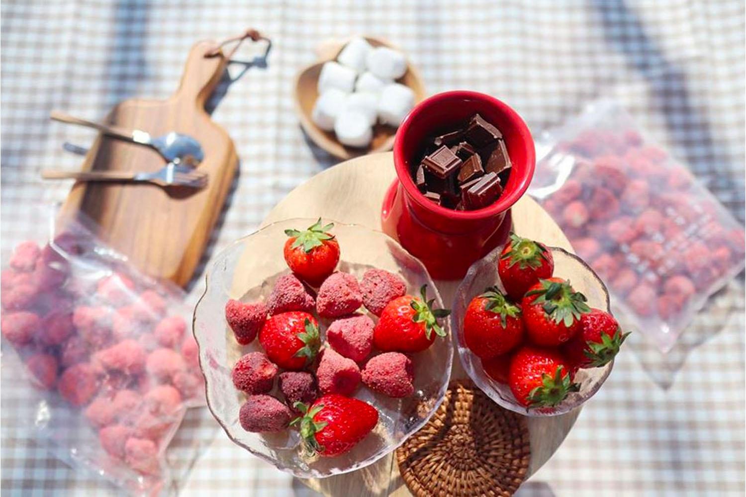 在桌上展示的韓國士多啤梨乾和巧克力火鍋，旁邊有新鮮士多啤梨和棉花糖，增添了休閒的野餐氣息。