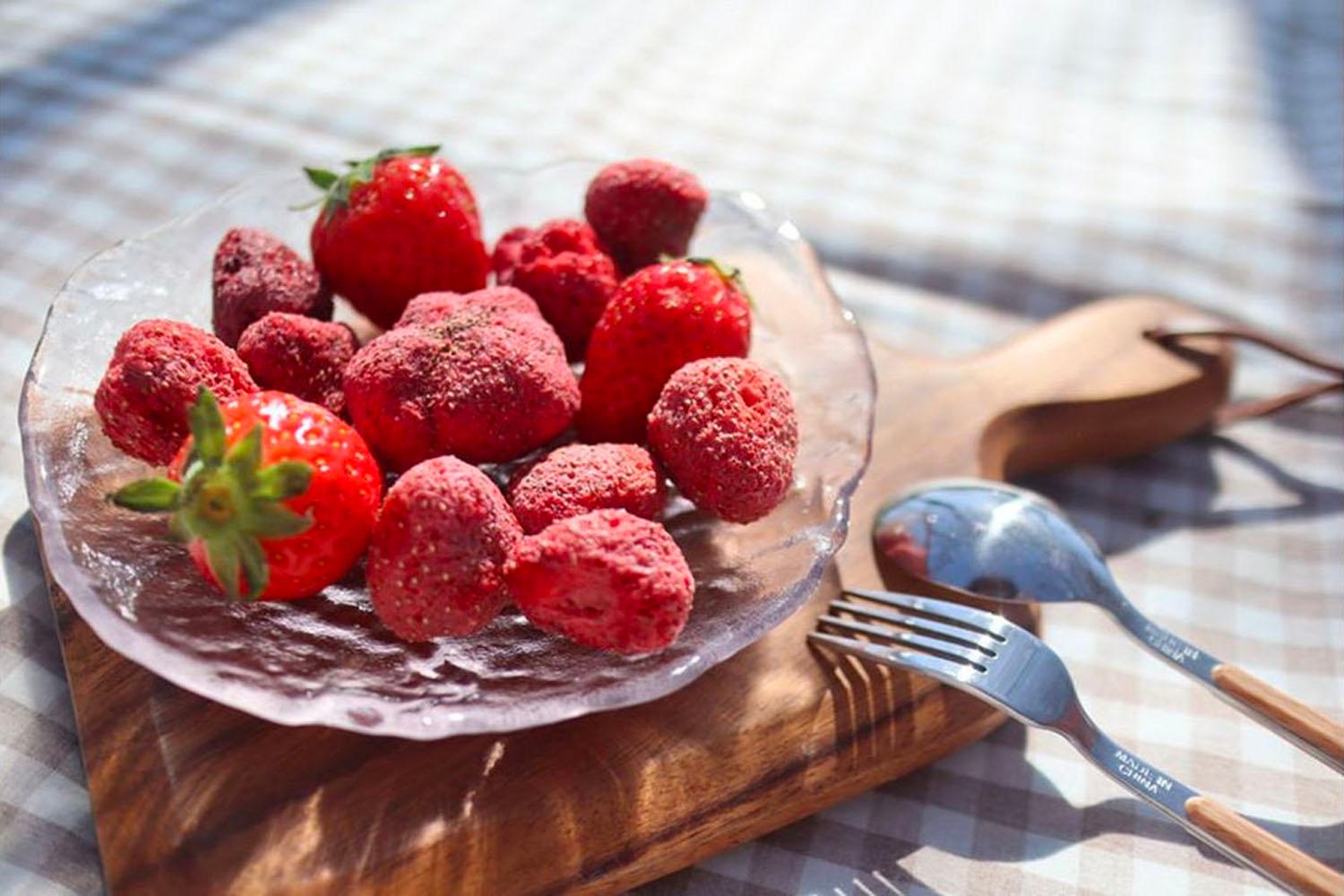 放在透明玻璃碟中的韓國南大門市場士多啤梨乾，在為陽光照射，與零食叉子一同擺放，散發出誘人的甜香氣味。