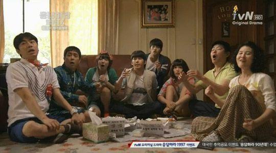 一群人坐在客廳裡,享受韓國炸雞和飲料的場景,展現家庭聚會的溫馨時刻。