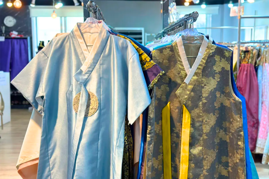Hanbok in pale blue and gold patterns hanging on display at Princess Hanbok in Seoul, ready for rental.