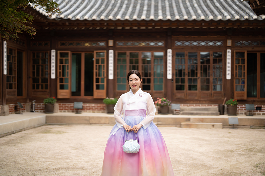 Enchanting view of a hanbok-clad individual sitting against the backdrop of a Korean palace gate, capturing a timeless moment.