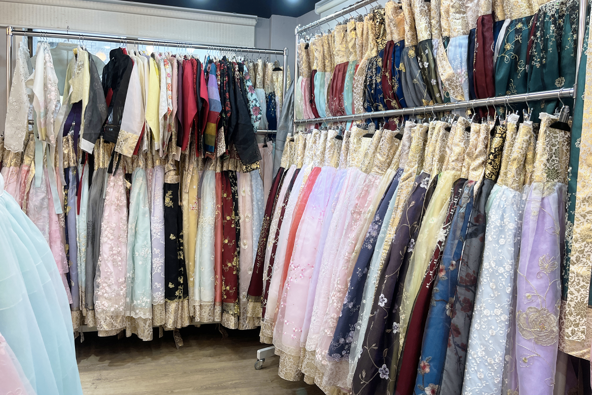 An array of hanboks hanging elegantly in the rental store, where visitors can choose from a spectrum of colors and patterns to experience Korean traditional dress.