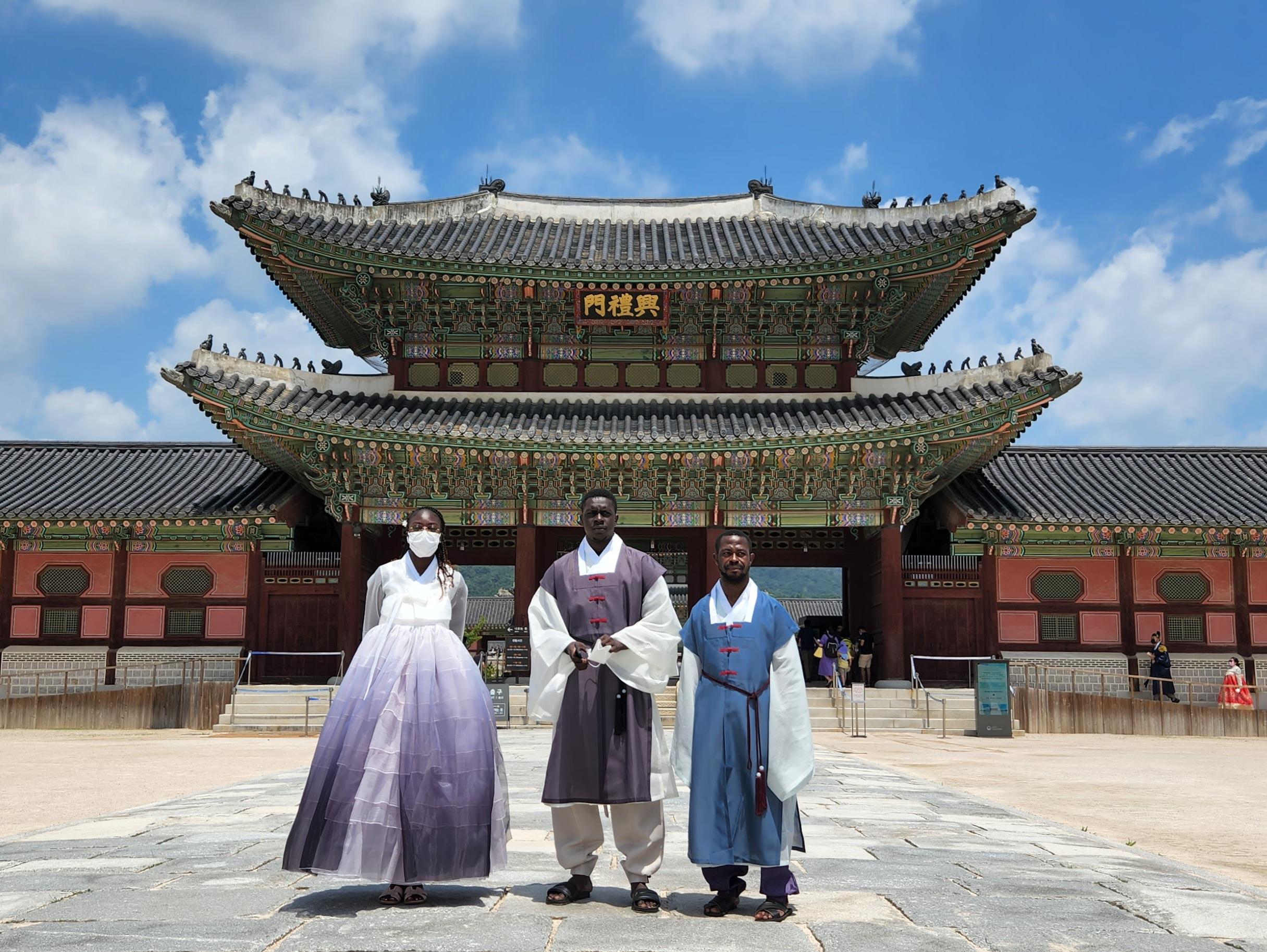 A picturesque scene with a woman wearing a hanbok, set against a lush green landscape, enhancing the traditional Korean attire with natural surroundings.