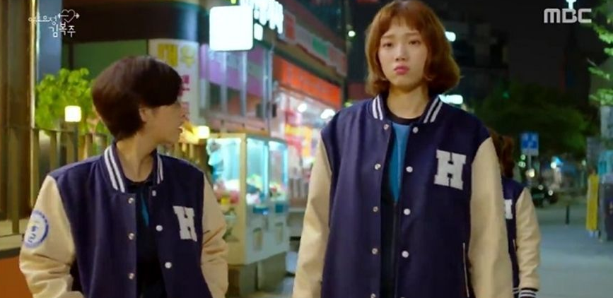 兩名穿著學校運動外套的學生，可能是在校園中的朋友互動場景。