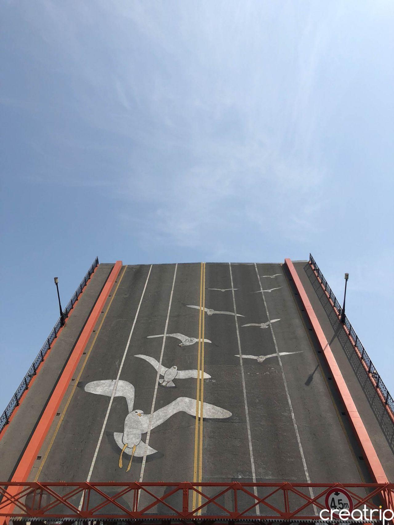 影島大橋開啟時的景象，橋面緩緩上升展示出橋下的海域，背景是清澈的藍天。