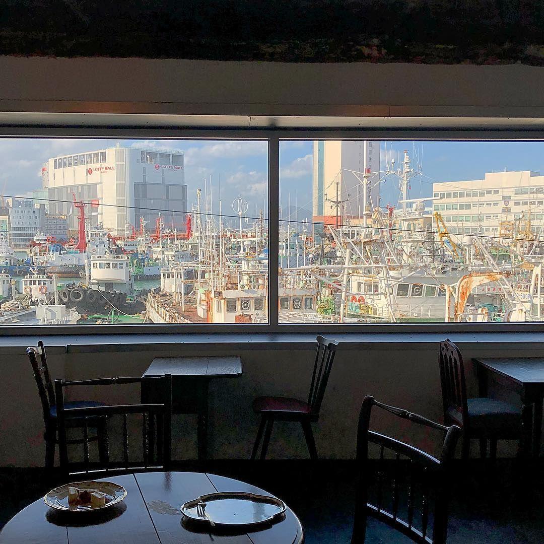 釜山影島上e.c.t.咖啡館的室內景觀，窗外滿是密集的漁船與遠處的高樓。