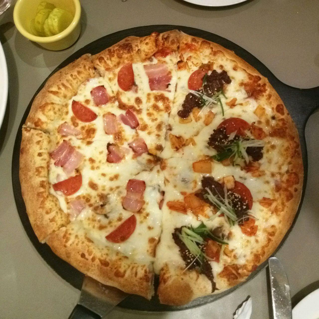 由姜丹尼爾推薦的釜山LEE JAE MO披薩，桌上展示有各種美味的披薩。