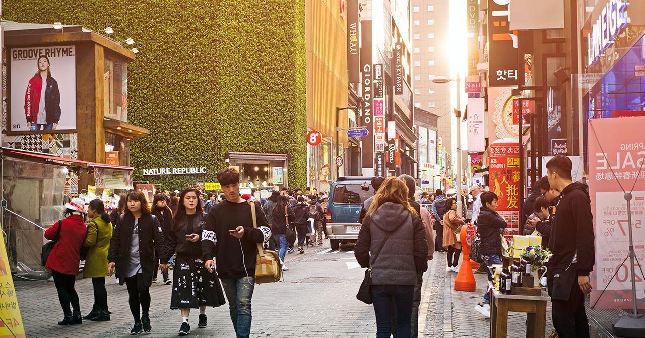 明洞鬧市景，熱鬧的商業街，滿是人群和門店廣告。