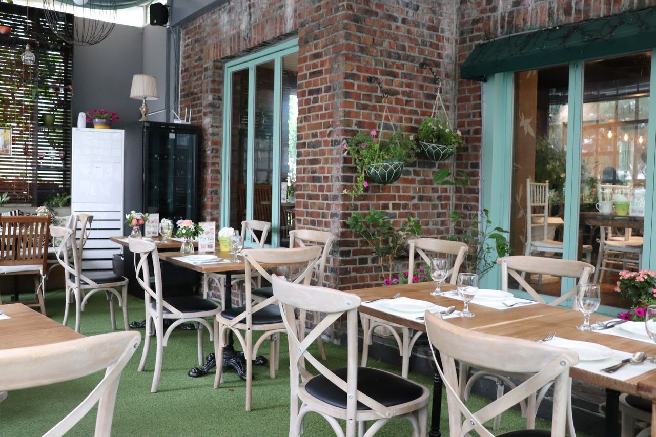 Urban Garden餐廳一樓的户外座位區,木製桌椅被綠色植物和鮮花點綴