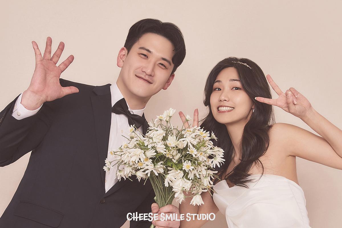 一對夫婦身著婚紗及西裝，在Cheese Smile Studio拍攝婚紗風格照片，手捧花束。