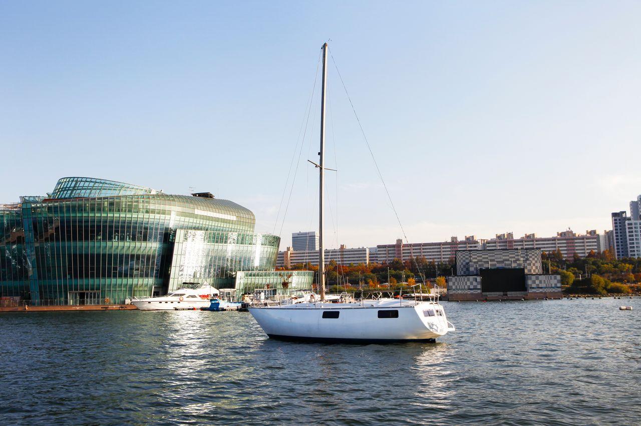 Elegant Sailing Yacht on the Han River in Seoul with a full view of the deck and sail against the city skyline.