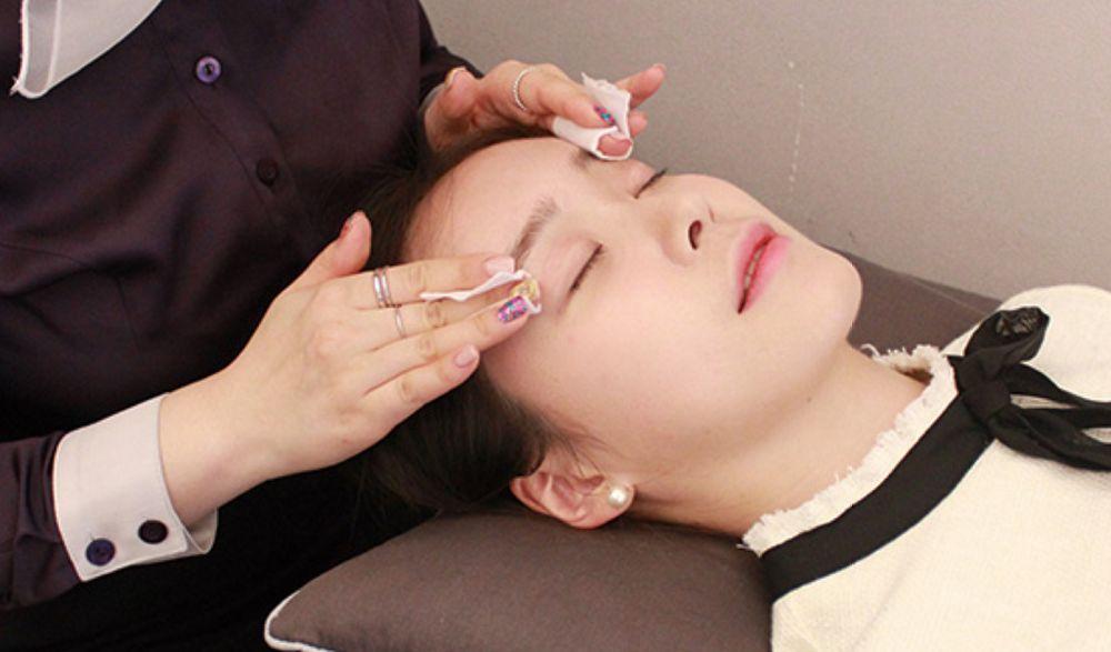 Application of numbing cream before semi-permanent eyebrow procedure at Juliet Beauty salon in Busan.