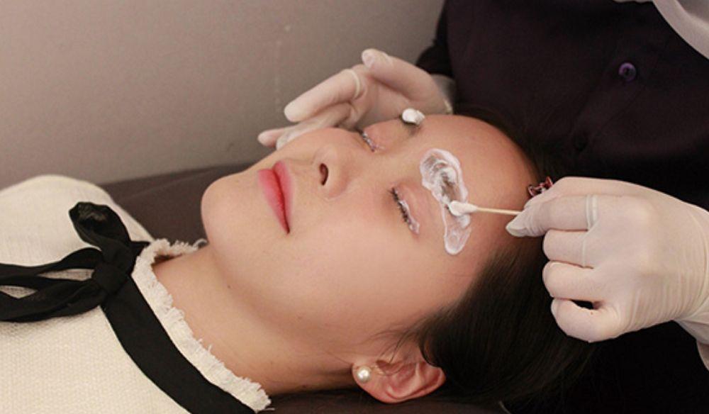 Technician applying numbing cream on a client before the eyebrow procedure at Juliet Beauty in Busan.