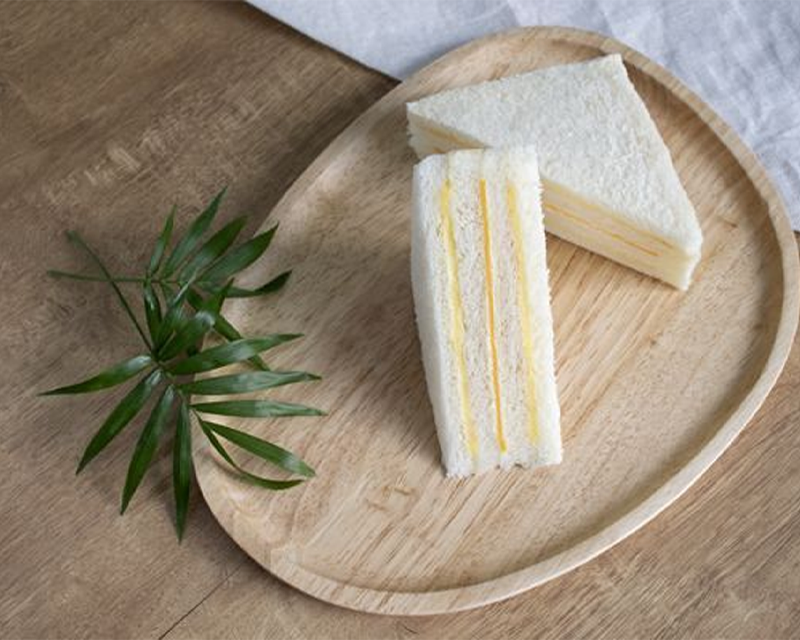 台式洪瑞珍三文治，細膩層次分明的三角形設計，置於木盤上。