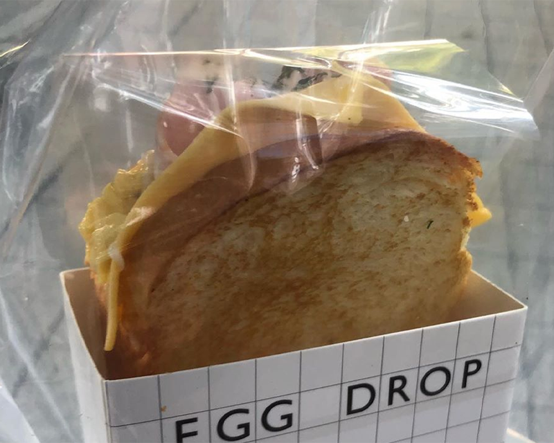 EGG DROP三文治，透明包裝中展示著豐富材料和醬汁的牛油吐司。