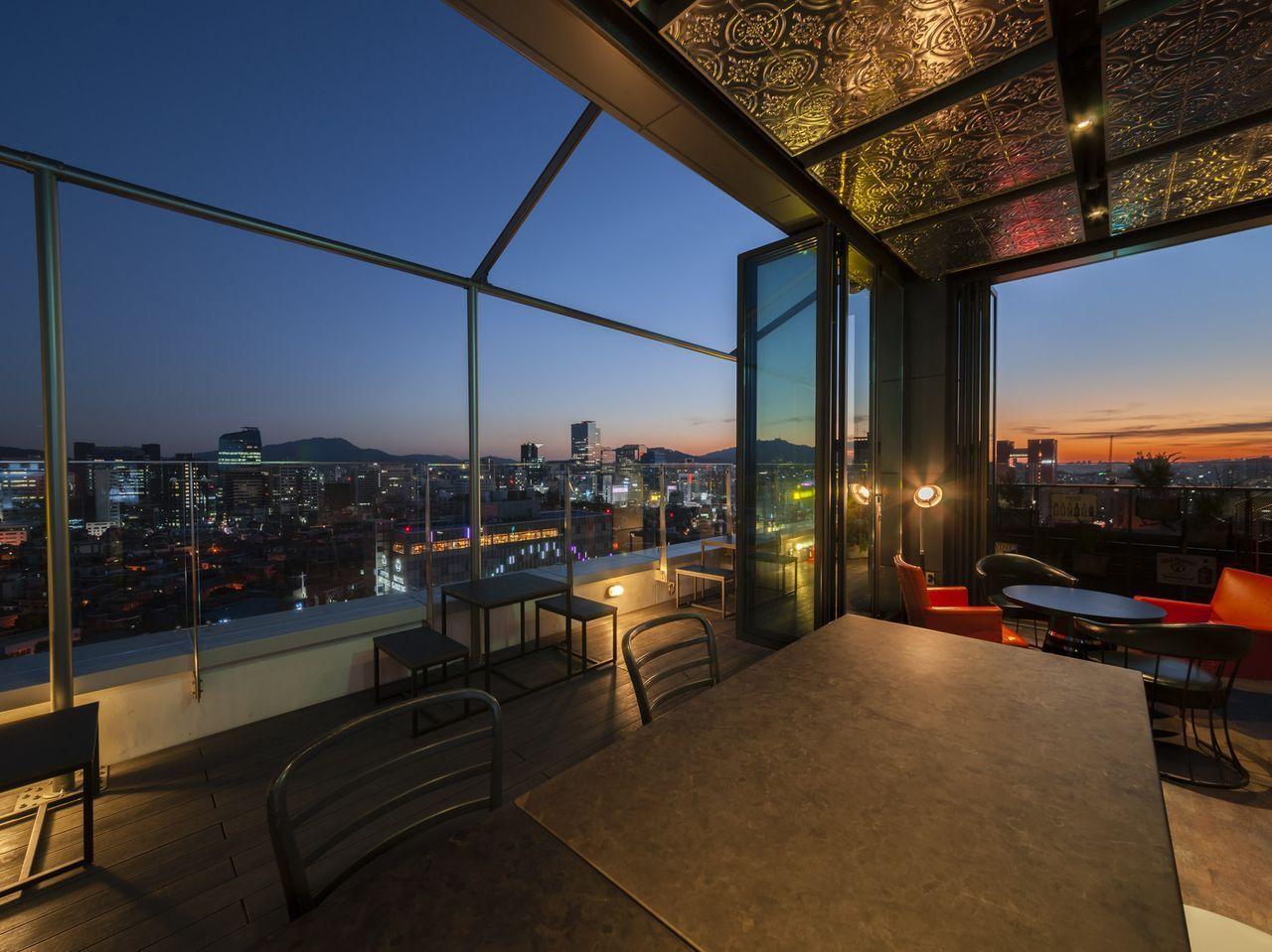 วิวอันทันสมัยของโรงแรมในเกาหลีที่มีบรรยากาศแบบลอฟท์พร้อมรูฟท็อปในยามพระอาทิตย์ตก