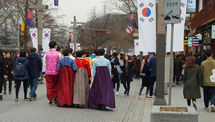 穿著鮮豔韓服的人們在韓國首爾街道上行走