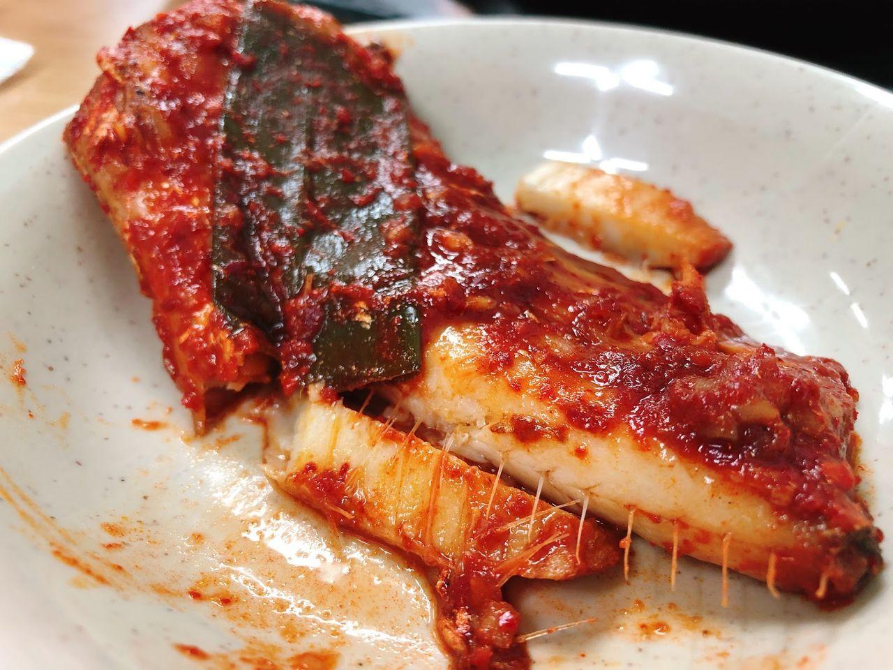 韓式辣燉白帶魚套餐，紅燒汁包裹的魚肉在傳統餐具內