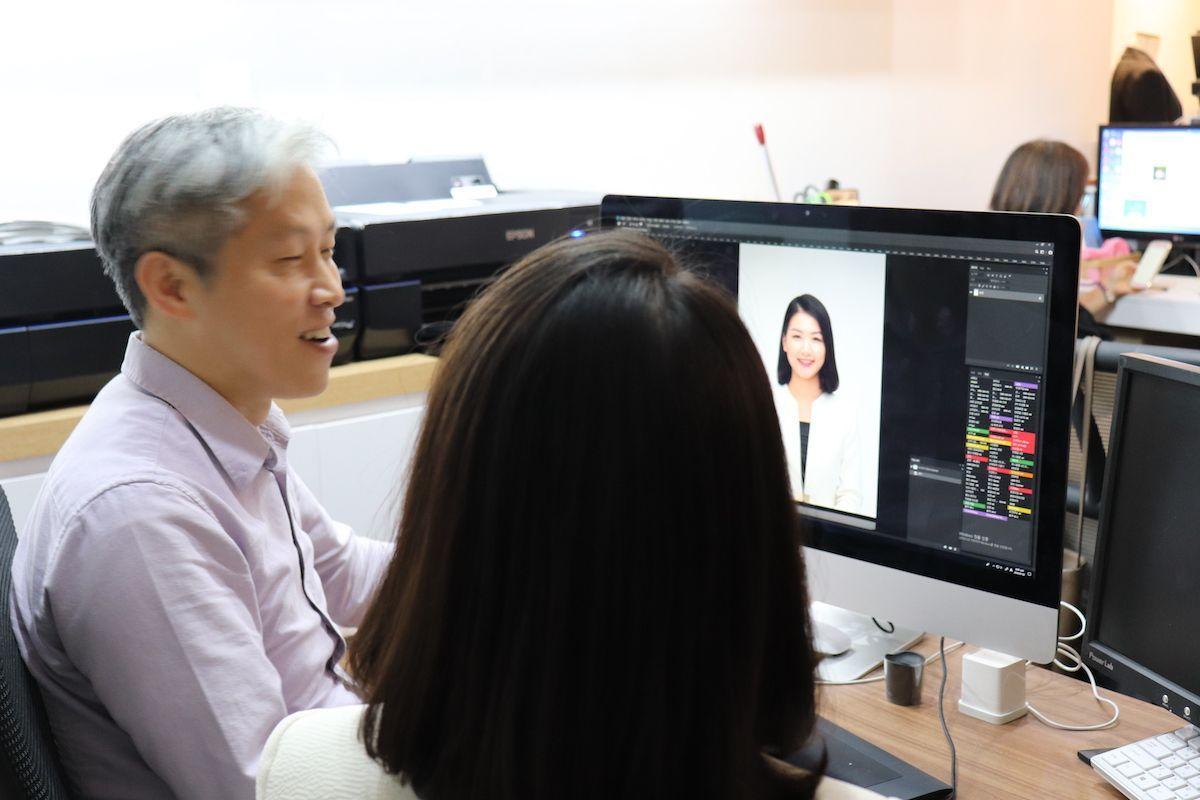 韓国の証明写真を撮影するフォトスタジオ、マンツーマンで写真修正を行う様子の画像