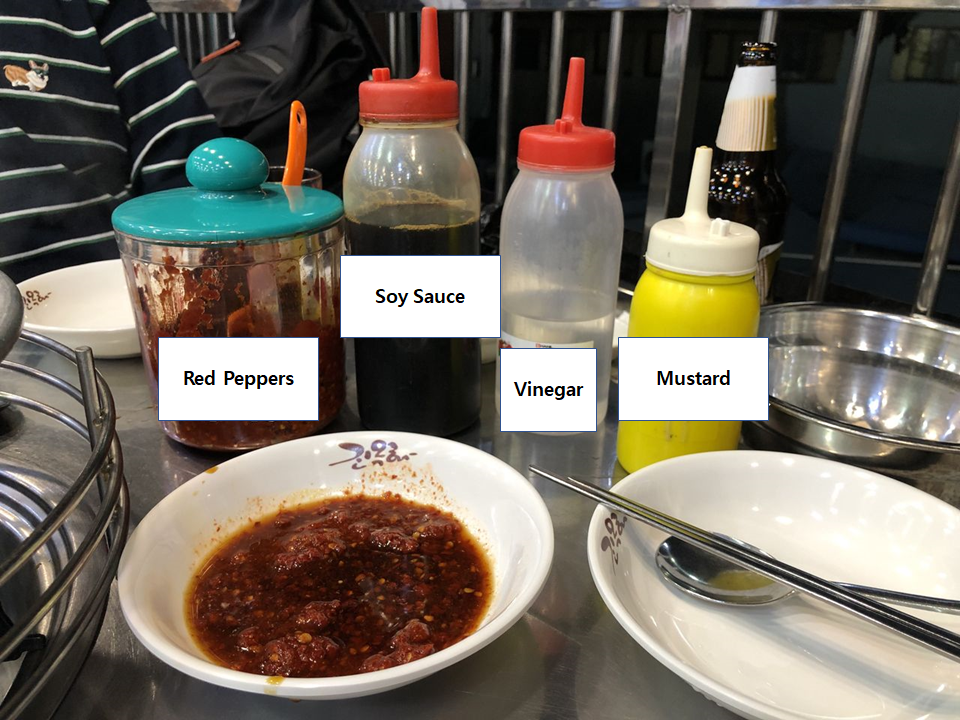 An array of condiments used at Jinokhwa Dakhanmari, featuring soy sauce, vinegar, mustard, and red pepper paste on a diner table.