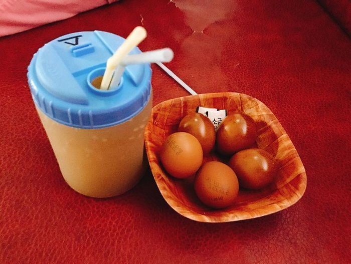 韓國汗蒸幕的經典搭配，冰鎮的飲品與幾顆烤蛋呈現於紅色桌面，提供一種韓式文化體驗。