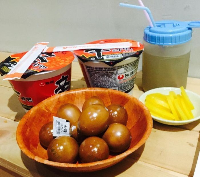 韓國汗蒸幕中的傳統零食，包含兩杯飲品、一碗韓式泡菜以及幾顆特製蛋，所有食物排列在木桌上。