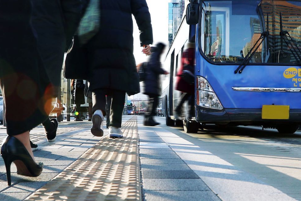 韓國首爾的公共交通場景，商務人士步入巴士，展示了城市交通的便利性