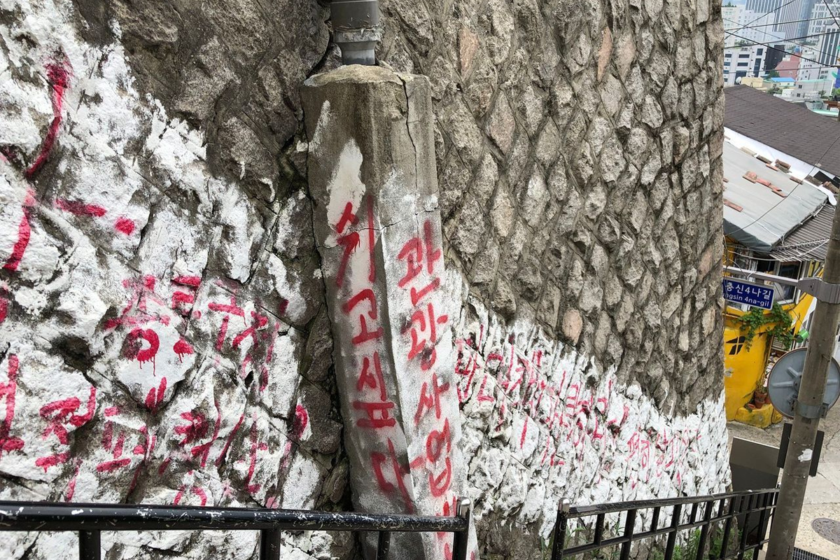 寫滿紅色字體的梨花壁畫村牆壁，顯示村民對於旅遊商業化的不滿