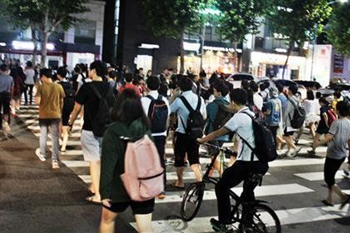 一羣晚間的韓國市民步行在首爾街頭，地鐵末班車前趕回家