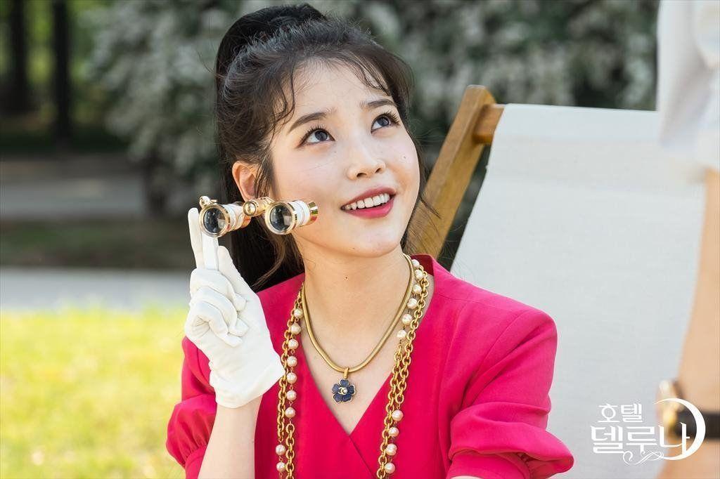 Personnage en robe noire élégante dans 'Hotel Del Luna', avec une atmosphère mystérieuse et une lumière diffuse.