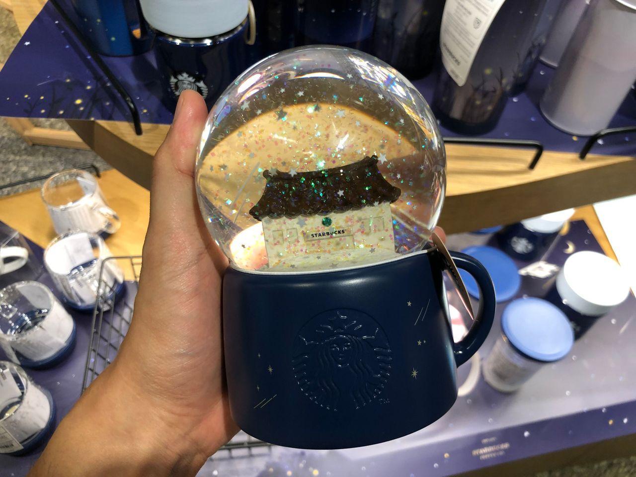 Эрхэсийн шоу дизайны ордоны цасан бөмбөг, дээд тал нь 'Starbucks' хээтэй, өнгөрсөн сэдэвт толгойтой.