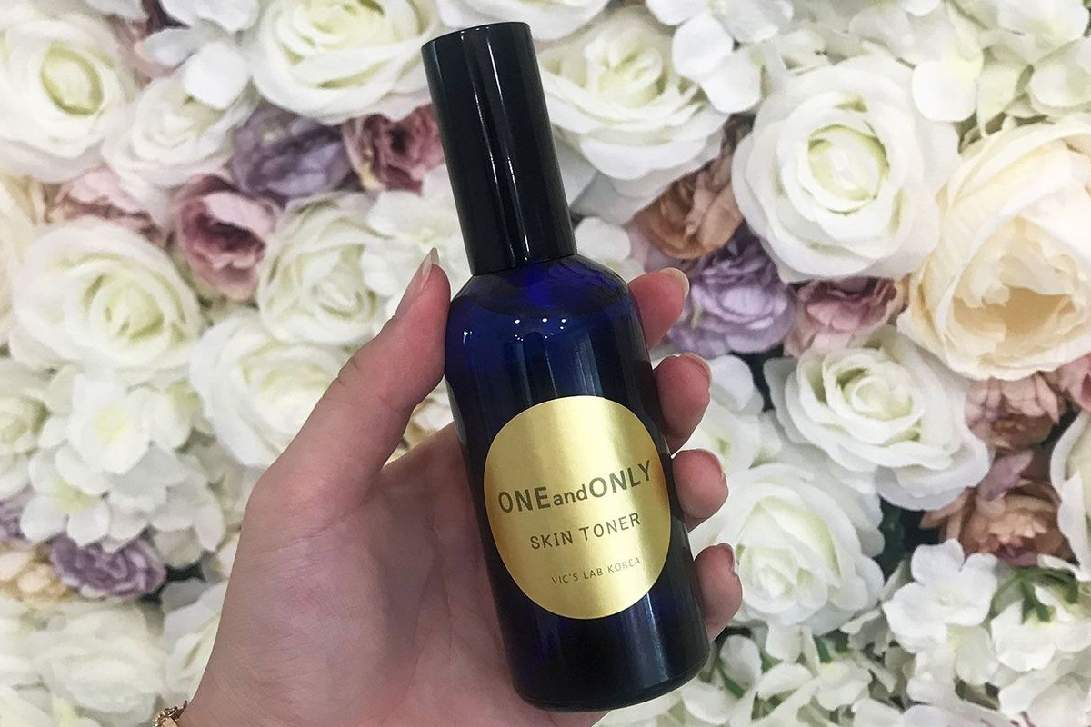 手に持たれた韓国オーガニックスキントナーのボトル、背景は美しい白い花々が飾られ、美容ケアのDIY体験が楽しめる延南洞のカフェNeulboで撮影。