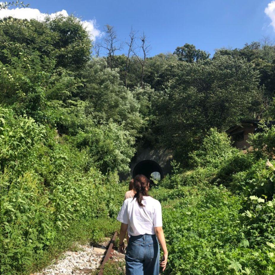 Deux personnes marchant le long des rails de chemin de fer, se dirigeant vers un tunnel à la station de Byukje.