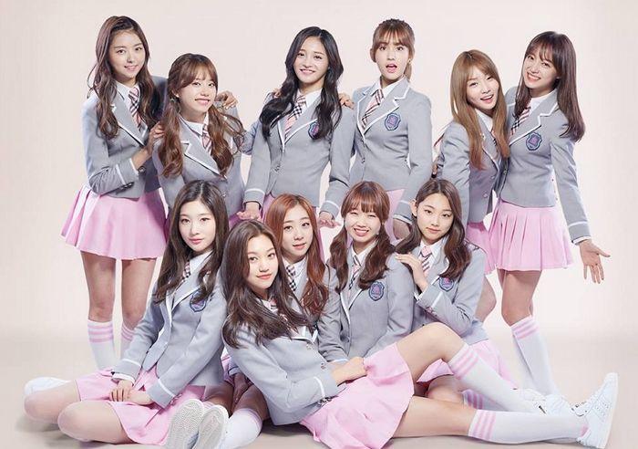 ภาพกลุ่มสมาชิกวงเกิร์ลกรุ๊ป IOI ขณะถ่ายภาพโปรโมตในชุดเครื่องแบบสีเทาและกระโปรงสีชมพู