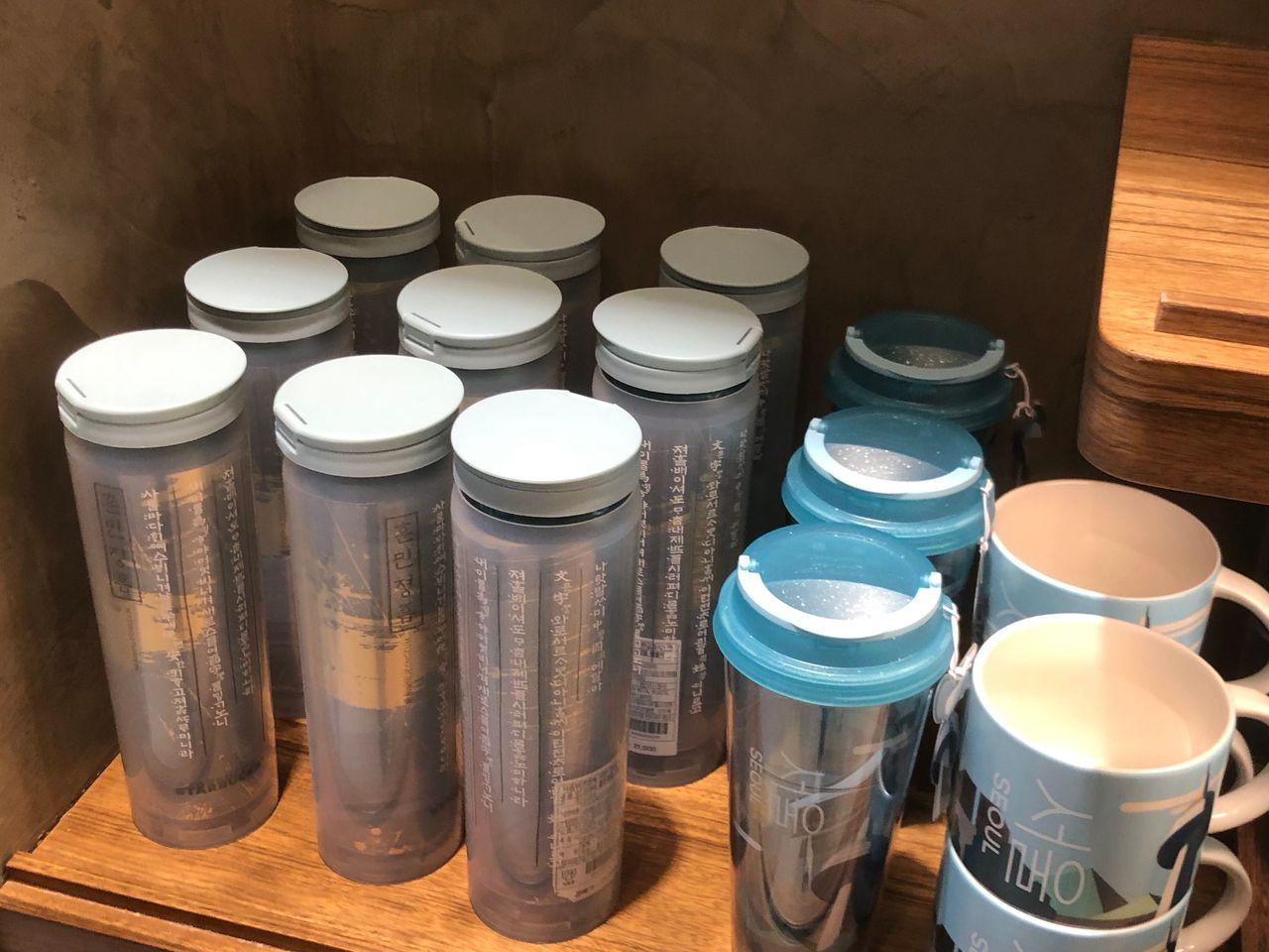 Starbucks Korea 20th anniversary tumblers and cups displayed on shelves.