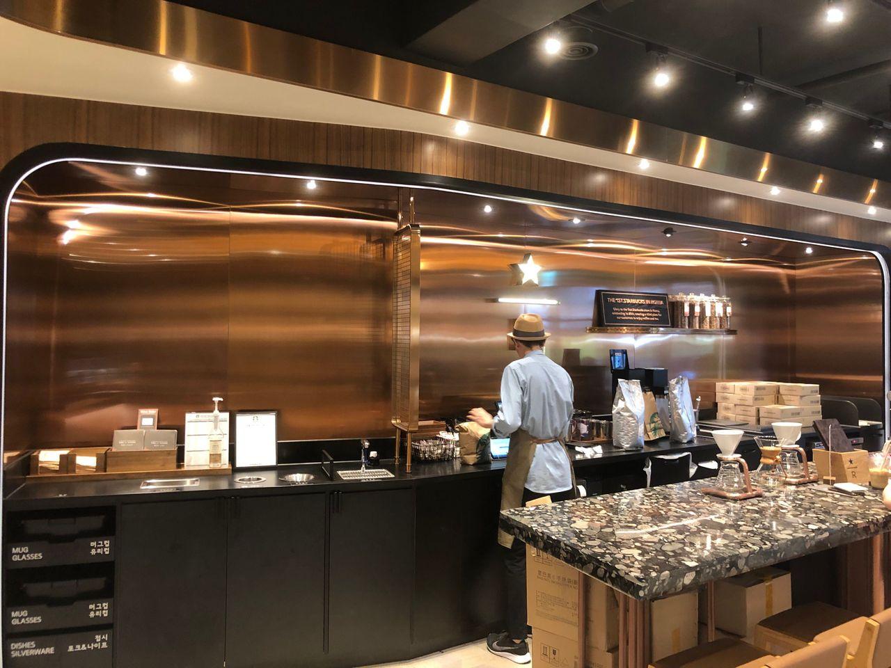 Barista preparing beverages at the elegantly designed bar of the first Starbucks in Korea.