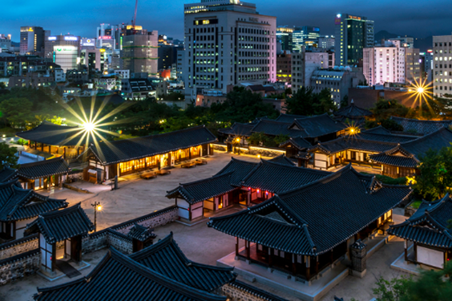 俯瞰南山谷韓屋村的夜景，展示精美的韓式建築和周圍城市景觀的完美融合。