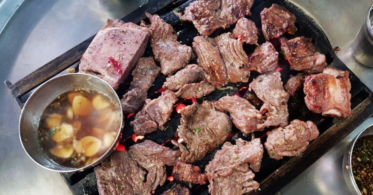 在新村享受站著吃的燒烤，一盤美味的烤肉搭配醬料，突顯出韓國燒烤的獨特風味。