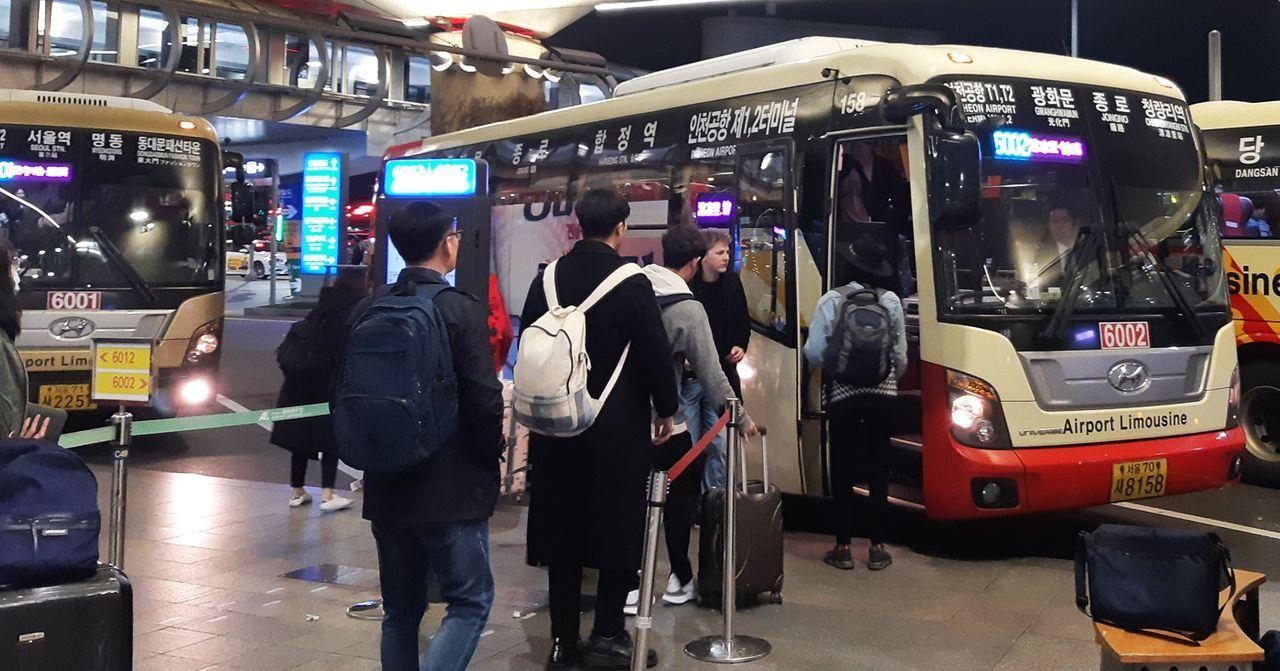 機場巴士上乘客正排隊登車，夜晚的機場氛圍，方便的交通選擇。